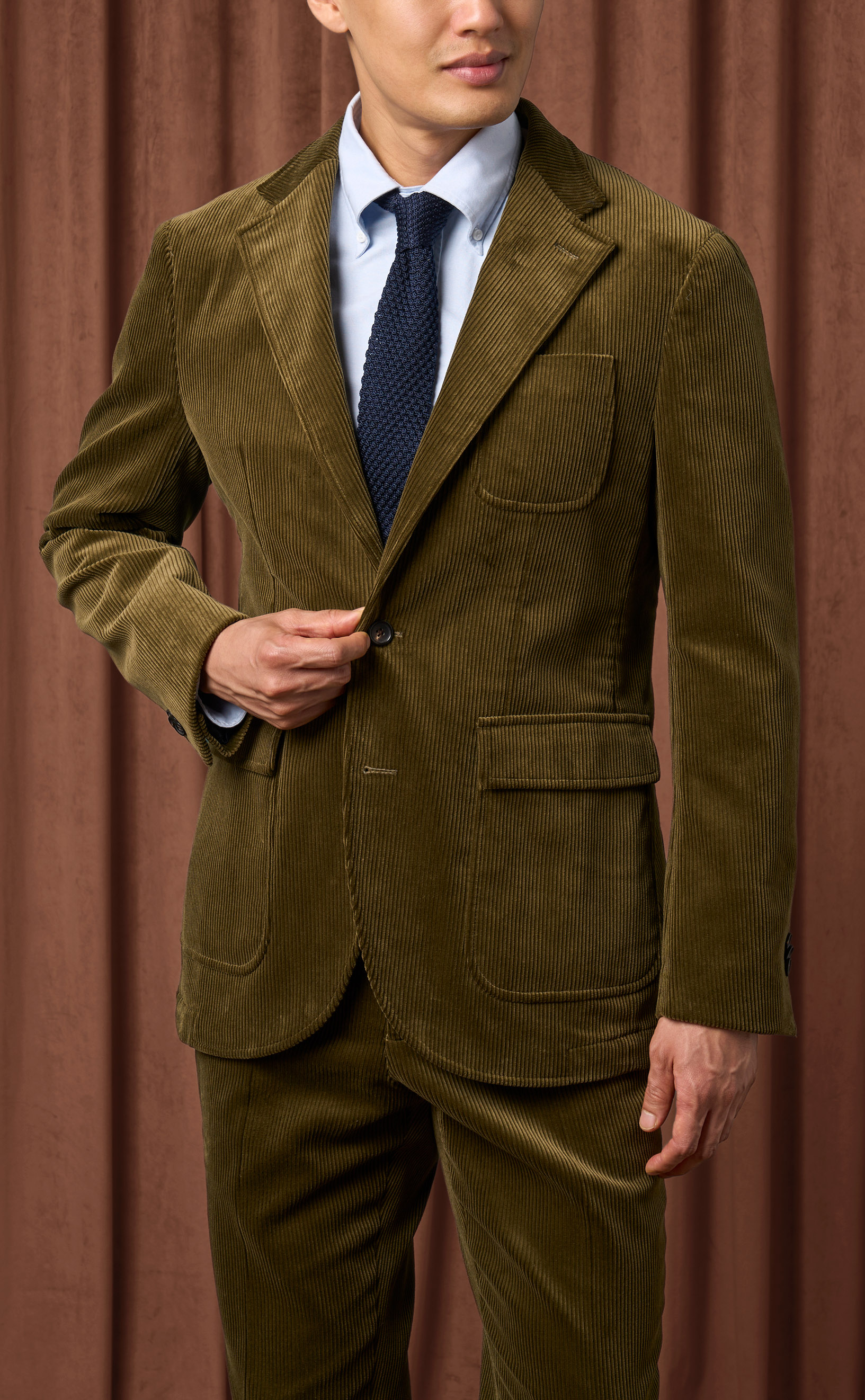 Tailor fitting a jacket, representing custom suiting